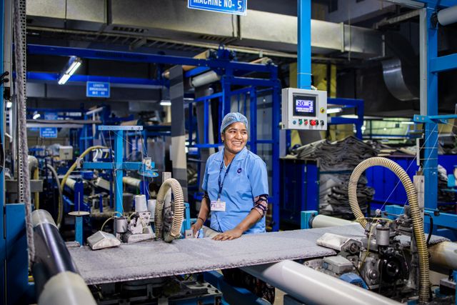 Factory worker operating textile production machinery — stock photograph